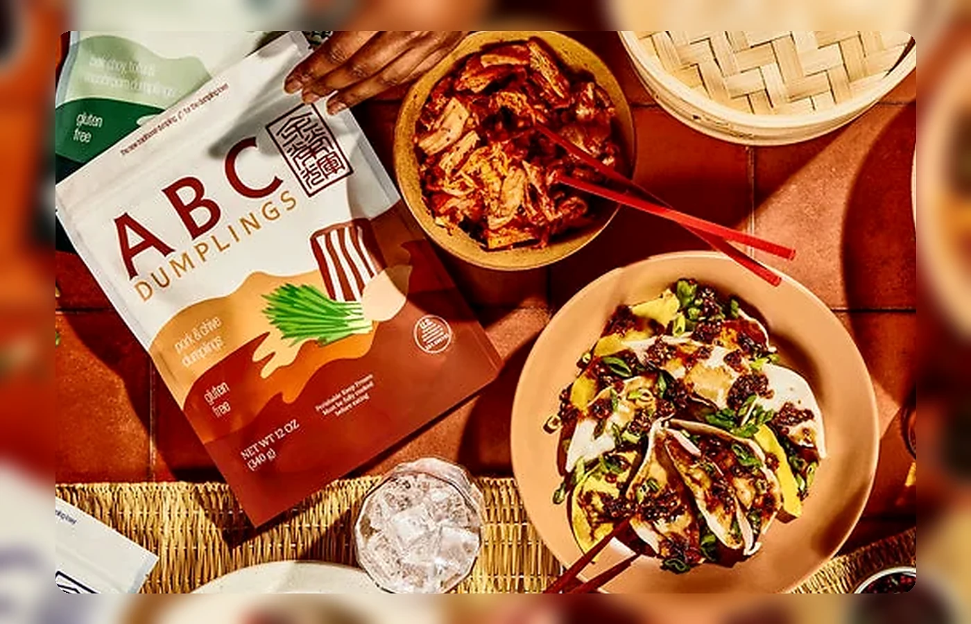 Kitchen table with frozen dumpling packs, an insulated grocery bag, a planning notebook and plated dumplings